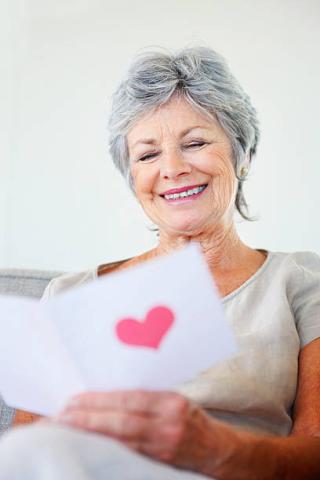 elderly woman reading a card with a heart on the front